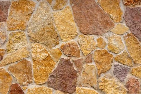Natural stone wall texture with irregular shapes and warm earthy tones Stock Photos