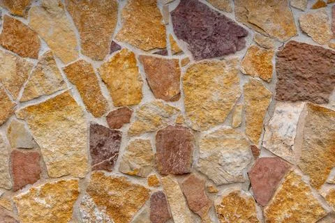Natural stone wall texture with irregular shapes and warm earthy tones Stock Photos