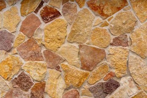 Natural stone wall texture with irregular shapes and warm earthy tones Stock Photos