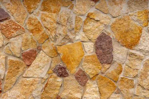 Natural stone wall texture with irregular shapes and warm earthy tones Stock Photos
