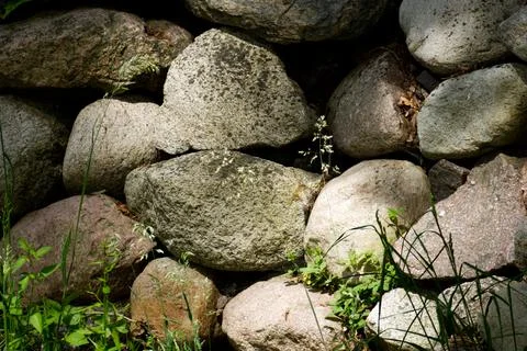 Natural stone wall texture with large cobblestones and green grass 写真素材