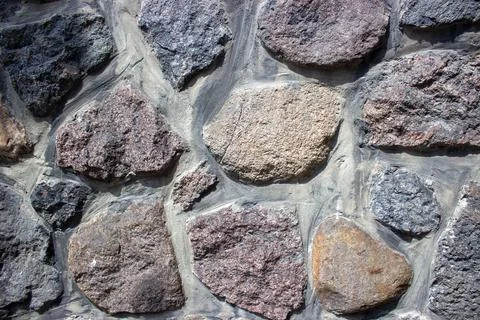 Natural stone wall texture with rough granite masonry pattern Stock Photos
