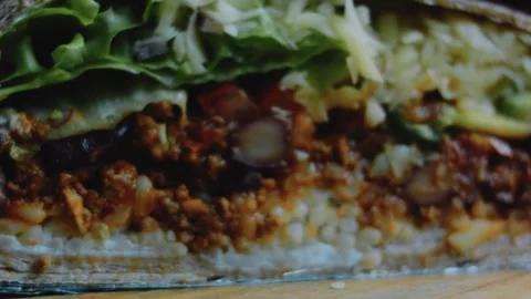 Natural tabletop view: foil-wrapped burrito cross section Stock Footage 342170878
