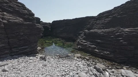 Natural tidal rock pool among dark slate cliffs on atlantic coastline Stock Footage 340456519