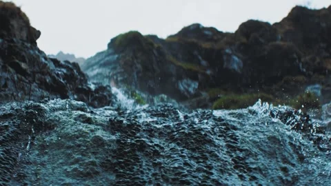 Natural water flow rushing over dark rocks in cinematic nature scene. Video stock 345006521