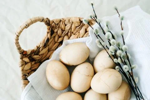 In a natural wicker basket, several Easter eggs with cracks on a white napkin Stock Photos