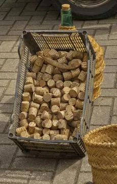 Natural wine corks fill a plastic crate beside wicker baskets and a glass c.. Stock Photos