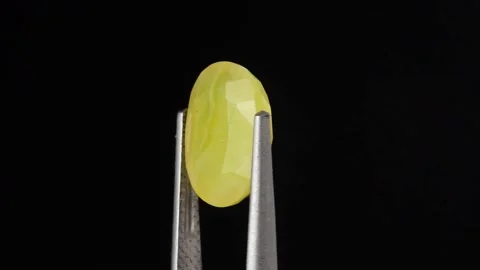Natural yellow fire opal gemstone in the tweezer on the background Stock Footage 169412322