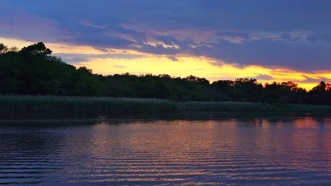 Nature landscape of a sunset, red and pink cloudy sky, on a lake Stock Footage