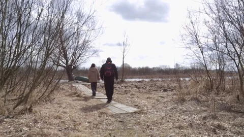 Nature lovers walking in spring field near lake shore. Stock Footage 310828683