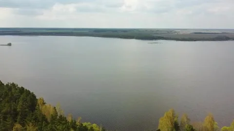 Nature view of a large lake surrounded by trees and distant fields in spring sea Stock Footage 328996863
