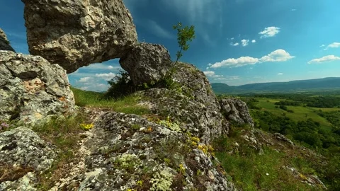 Nature's ancient arch frames distant green hills. Vrmdza Fortress. Serbia Stock-Footage 338021469