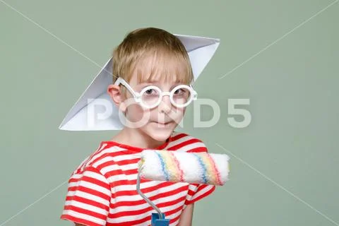 Naughty boy in a paper hat and glasses with roller for painting. Portrait. Stock Photos