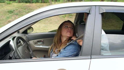 A naughty boy is playing and indulging in a car, he prevents mother to drive. Stock Footage 114978221