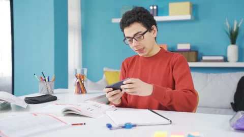 The naughty boy plays on the phone instead of studying, and then he wakes up. Stock-Footage 234090442