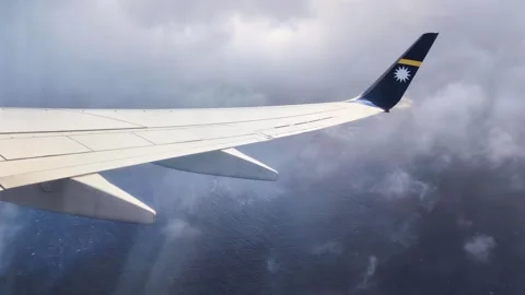 Nauru Airline airplane window view flying through clouds over ocean Federated Stock Footage 345894333