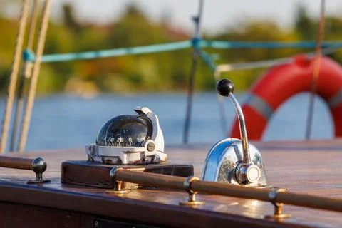Nautical compass and chrome throttle lever on the wooden deck of a yacht wi.. Photos