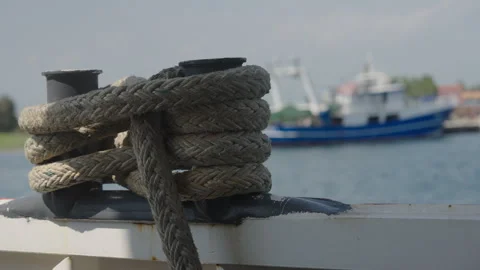 Nautical Rope Securely Tied on Dock Bollard with Fishing Boat in Background Stock Footage 338018649