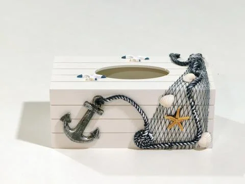 Nautical tissue box featuring anchor, lifebuoy, and fishing net on rustic wood b Foto stock