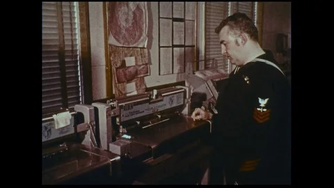 A naval officer awaits the printing of faxed weather information while another Stock Footage
