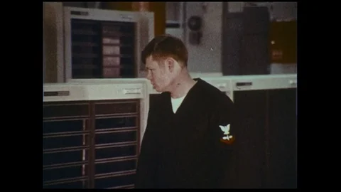 A naval officer checks computer data at a naval fleet numerical weather center. 库存影片 74519496
