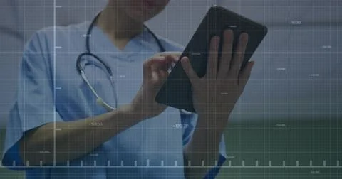 Navigating data grid, nurse in blue scrubs with stethoscope tapping tablet in Stock Photos