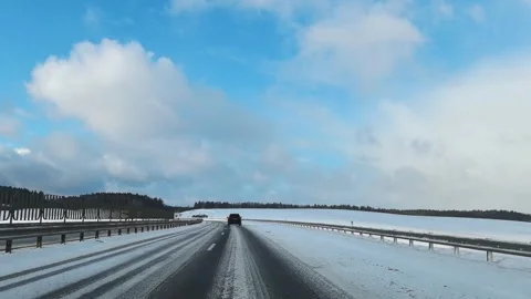 Navigating a snowy road in a tranquil, remote area, surrounded by clear blue ski Vídeos de archivo 344928207