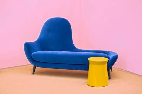 Navy blue sofa on a pink background, laconic interior. Stock Photos