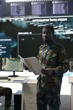 Navy operations specialist reading new mission case files in command center 库存照片