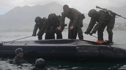 Navy Seals train on rubber zodiac watercraft while a helicopter performs a Stock Footage