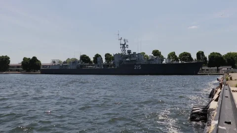 Navy ship docked in a harbor during the day. Military boat floating on water Stock Footage 90978122
