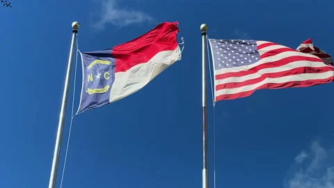 NC and USA flags blowing against a blue sky Stock Footage 165417449