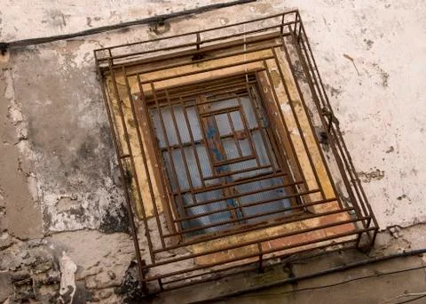 Ncient window with rusty and battered security grille - dutch tilt Stock Photos
