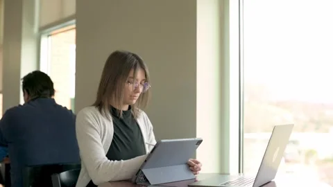 Nderstand or interact with digital learning tool on her tablet, with laptop o Stock Footage 274656768