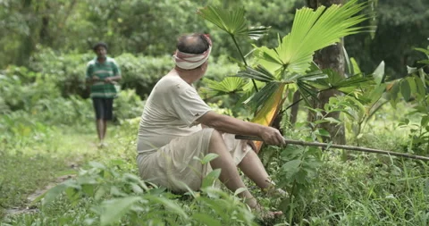 Ndigenous Asian man using a traditional net for fishing while sitting on a Stock Footage 346754668