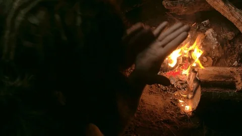 Neanderthal man warms his hands by the first bonfire in his cave Stock Footage