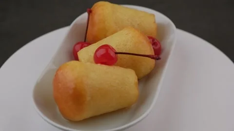 Neapolitan Rum baba on a white plate with a cocktail cherry. Stock Footage 172255316
