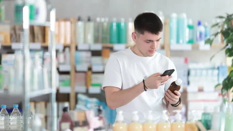 Near display case in pharmacy, guy scans barcode on antitussive syrup Stock Footage 317530618