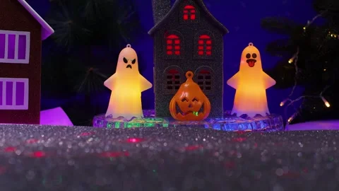Near the small gray house there is a pumpkin figure and glowing ghost figures Stock Footage 346601660