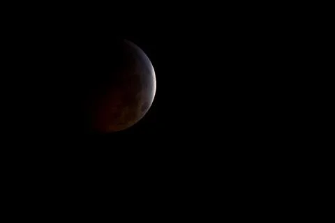 A nearly total lunar eclipse is seen as the full moon is shadowed by the Ea.. Fotos Stock