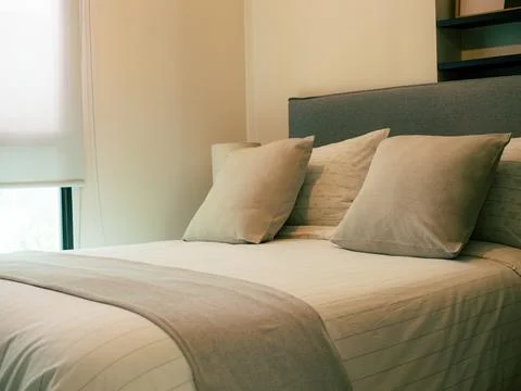 Neat bed with white sheets and gray blanket Stock Photos