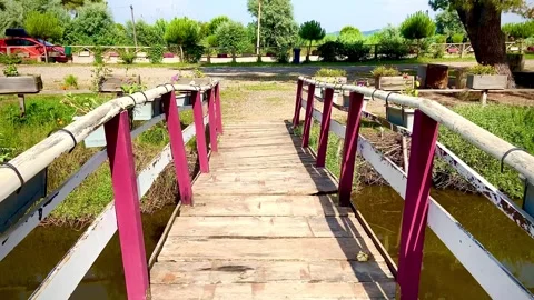 Neat small bridge across a small river with plank flooring and railings Stock Footage 249184218