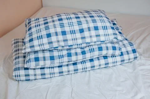 Neat stack of bedding pillows and a duvet lie on the bed Stock Photos