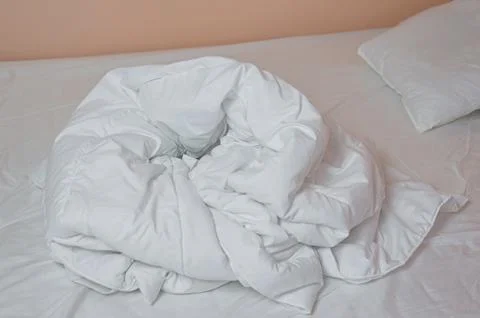 Neat stack of bedding pillows and a duvet lie on the bed Stock Photos