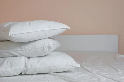 Neat stack of bedding pillows and a duvet lie on the bed Stock Photos
