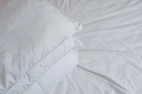 Neat stack of bedding pillows and a duvet lie on the bed Stock Photos