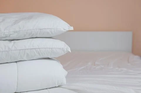 Neat stack of bedding pillows and a duvet lie on the bed Stock Photos