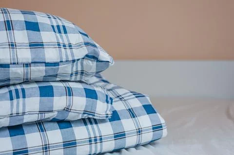 Neat stack of bedding pillows and a duvet lie on the bed Stock Photos