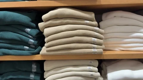 A neat stack of new sweaters in light and blue colors with visible size stickers Stock Footage 323715249