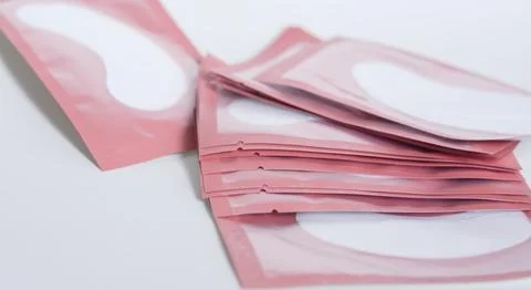 A neat stack of pink hydrogel eye patch sachets for professional lash isolati Stock Photos